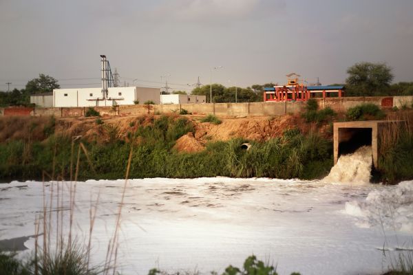 A sewage lagoon with facilities in background