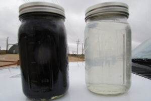 A jar of dirty produced water next to a jar of treated produced water